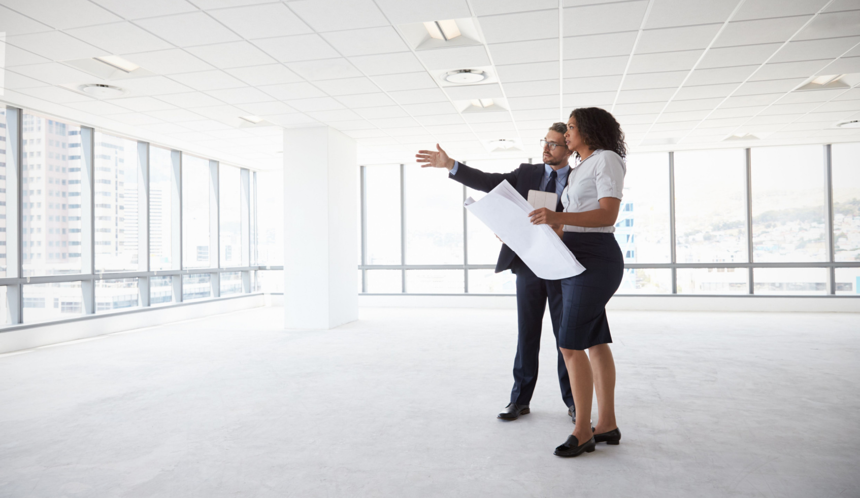 Businesspeople Meeting To Look At Plans In Empty Office